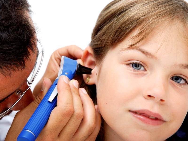 Audiologist checking a girls ear.